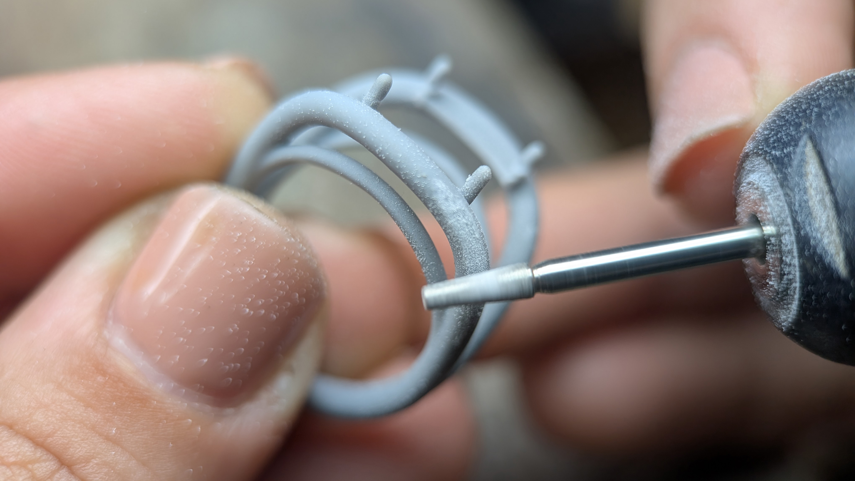 Prototipo de joyería en gris sujeto contra un micromotor