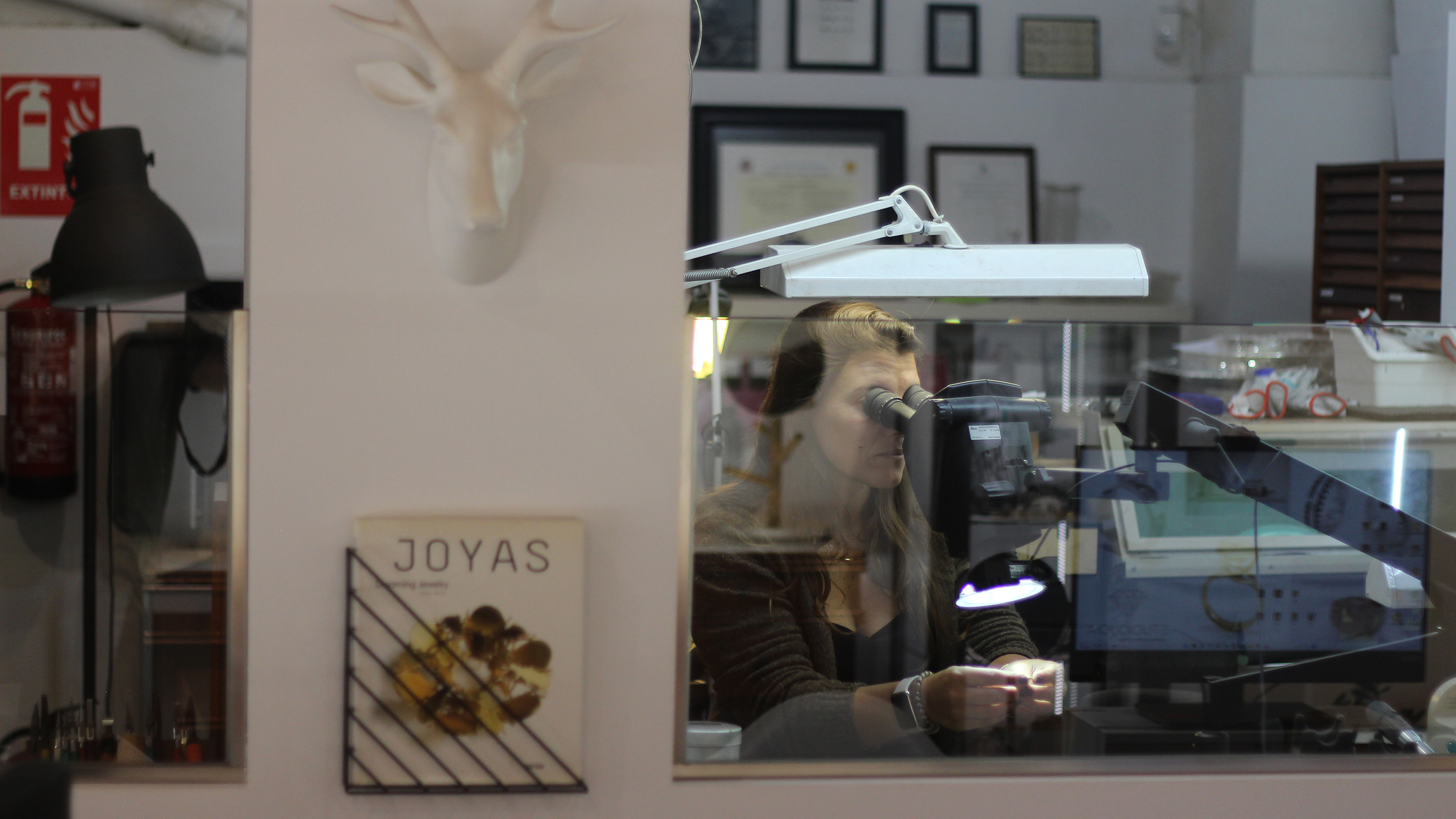 Diana trabajando con un microscopio en una pieza de joyería